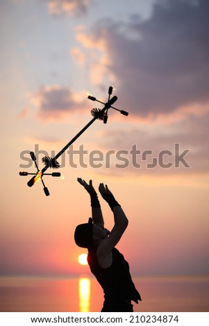 Silhouette of fire magician juggling with a fire baton