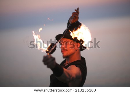 Portrait of fire dancer spinning poi over his head
