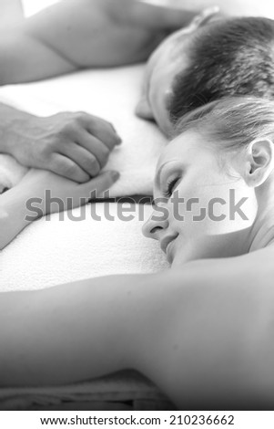 Woman and man sleeping holding hands, spa salon; monochrome