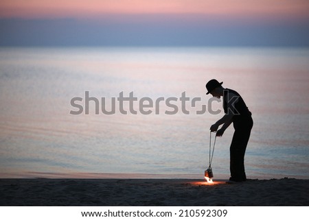Man setting fire to poi on the beach, preparing for fire show