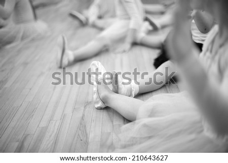 Small ballerinas stretching legs;monochrome