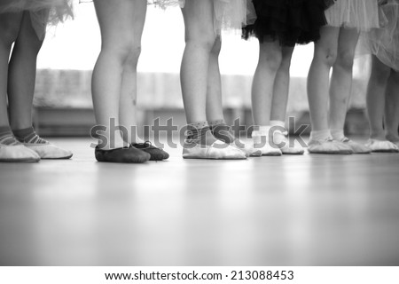 Legs of small ballerinas standing in a row, monochrome