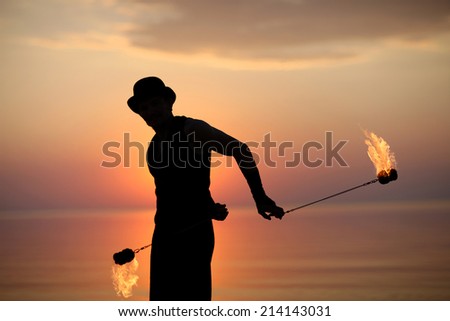 Silhouette of a man spinning fire poi