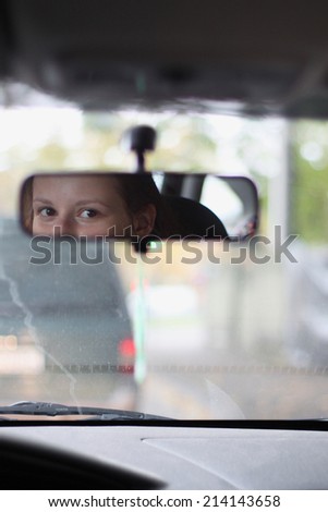 Eyes of a young driver in rear-view mirror