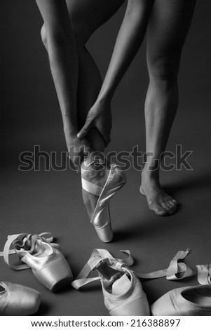 Beautiful athletic legs of a woman in one pointe shoe, monochrome