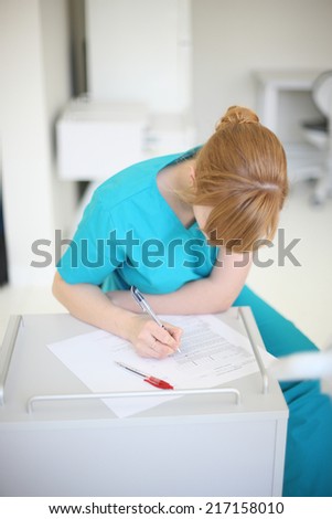 Young doctor writing treatment plan in clinic