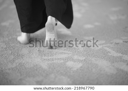 Low section of man barefoot walking on beach, monochrome