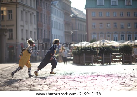 Fellow clowns running through the streets of the city, street theater concept