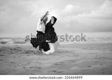 Dynamic aikido training on the beach, monochrome