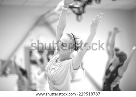 Women stretching hands up in fitness class, monochrome