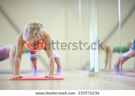 Woman press ups next to the mirror in gym