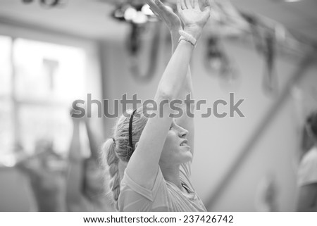 Close up of woman lifted arms in fitness class, monochrome