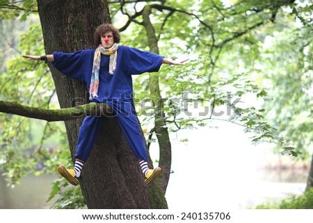 Clown mischiefing on the tree branch, street theater concept