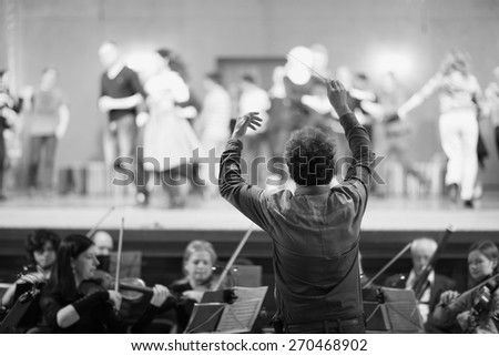 Orchestra conductor leading the musicians in the theater