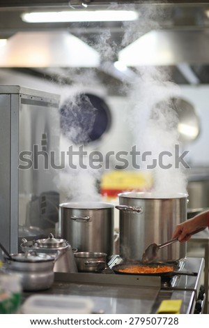 Cooking in a restaurant kitchen, steam over cooking pots
