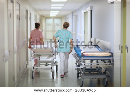 Nurses pushing a mobile bed in a hospital corridor