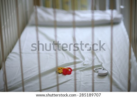 Closeup of a empty baby\'s crib with left toys