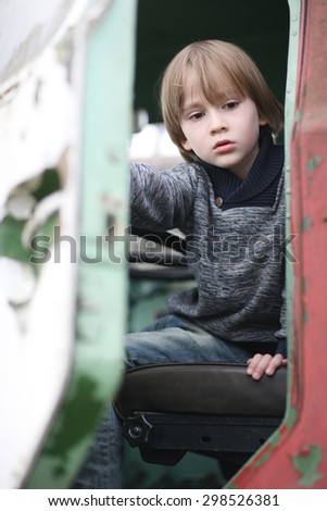 Child with sad facial expression getting out of an old driver cabin