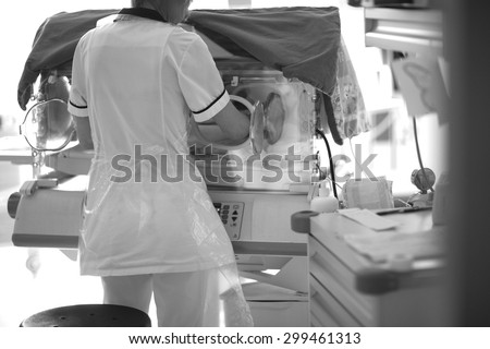 Medical checkup in neonatal intensive care unit; back of a doctor opening baby incubator