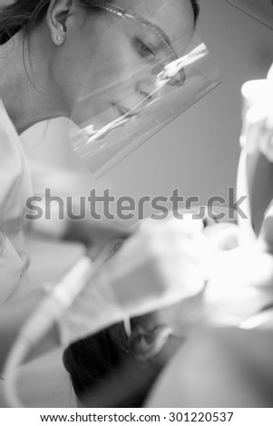 Beautiful female dentist drilling, dental restoring therapy