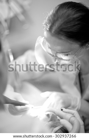 General dental practitioner\'s practice; female doctor examining patient\'s teeth