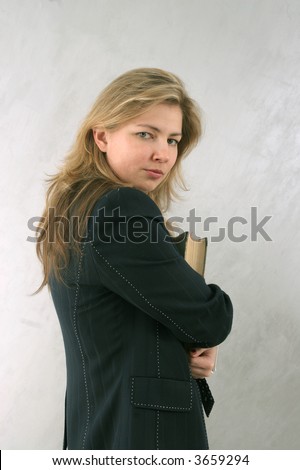 portrait of woman holding book and looking over her shoulder
