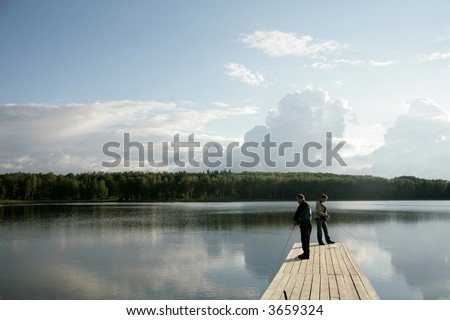 two men standing on pier and fishing