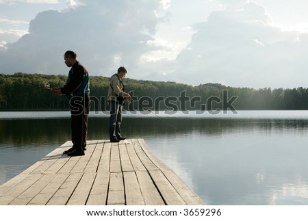 two men standing on pier and fishing
