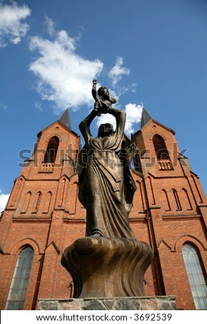 bronze statue of Jesus mother before a red brick church