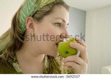 close-up of woman wearing green blouse and headband eating apple