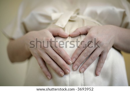 pregnant woman holding hands in shape of heart on belly