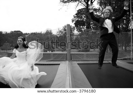 bride and groom jumping on trampoline - black and white