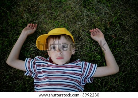 boy laying in grass with confused face expression