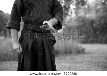 man in kimono holding samurai sword, black and white