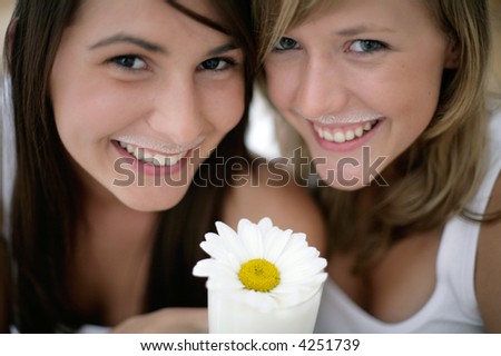two girls with milk mustaches and glass of milk with white flower