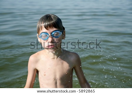 young boy bursts out of lake, dripping water from face