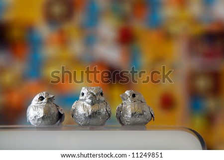 three tiny birds sitting on display