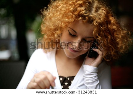 happy curly red haired girl listening to someone who called her