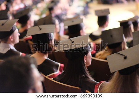 Square academic caps of graduates sitting in the university hall at the presentation of diplomas.