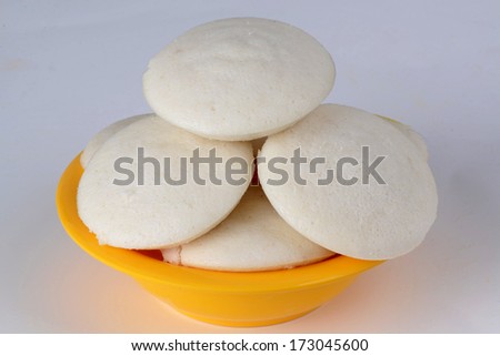 Idli on white background -  A traditional ethnic south Indian breakfast of Idly (Idli / rice cake) served with tomato chutney, coconut chutney and sambar on a plate lined with banana leaf.