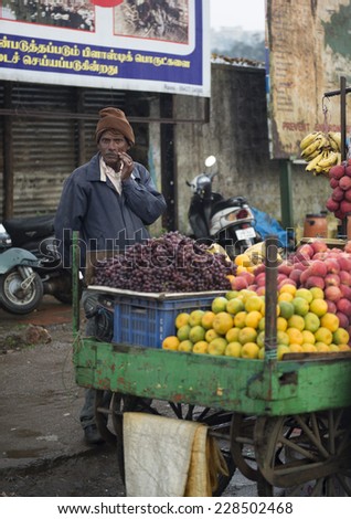 OOTY, TAMILNADU SEPTEMBER 25: Fruit seller selling fruits on the roadside vehicle shop on rainy day in Ooty, Tamilnadu, India on Sep 25, 2014