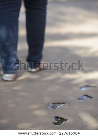 Pregnant woman walking baby foot steps behind her following.