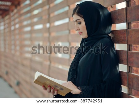 Emarati Arab woman outside reading a book, Dubai, United Arab Emirates.