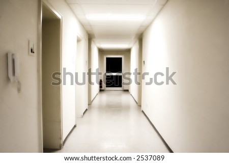 White corridor with black door at the end