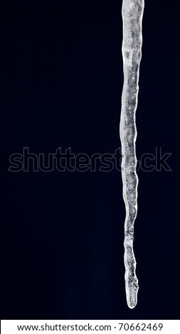 Close up a frozen icicle formation isolated on black with detailed crystal formation visible inside the icicle.