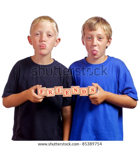 Young boys goofing around sticking their tongues out while holding wood blocks that spell out the word \