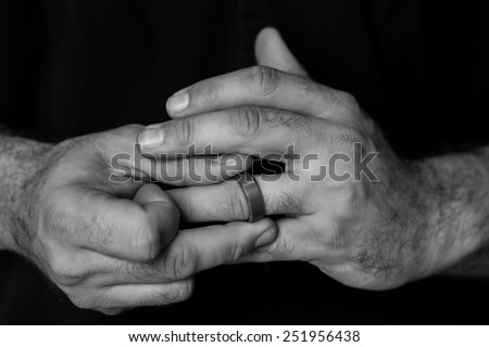Black and white detail of a man\'s hands fidgeting with a wedding ring