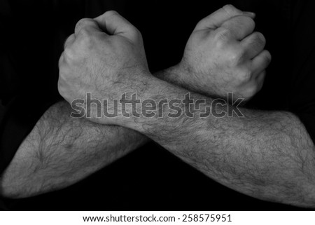 Black and white image of a mans arms crossed over each other