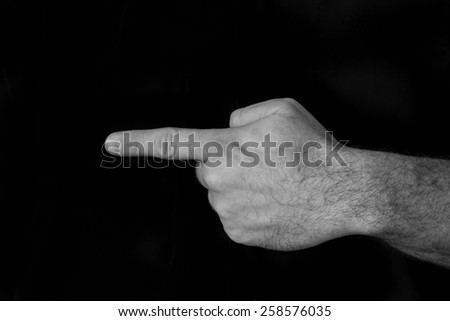 Black and white image of a hand pointing to the left with a black background