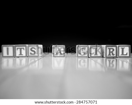 Black and white image of toy blocks on a wooden floor spelling out \